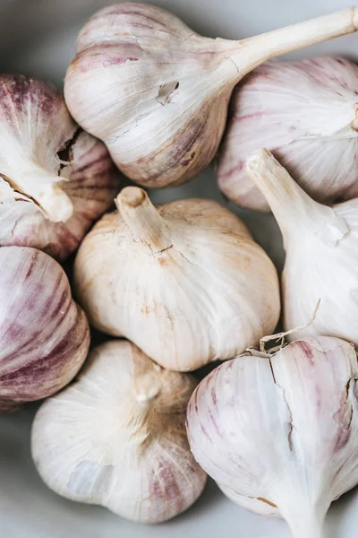 Primer plano de las cabezas de ajo maduras en tazón de cerámica blanca - foto de stock