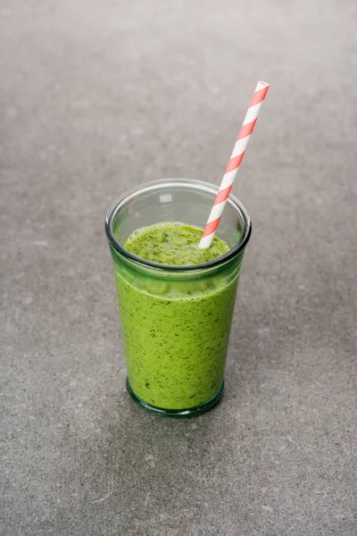 Batido verde y saludable mezclado en vidrio con paja - foto de stock