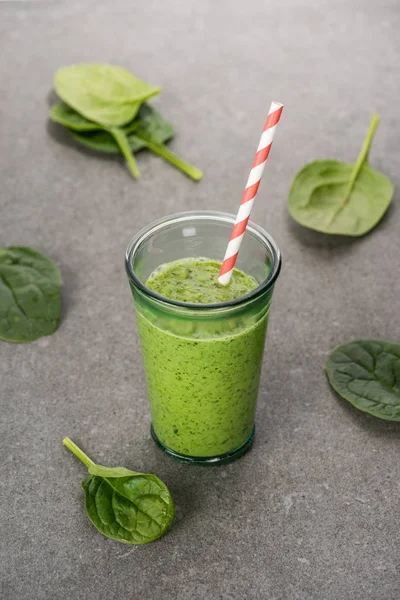 Hojas de espinaca y batido orgánico verde en vidrio con paja - foto de stock