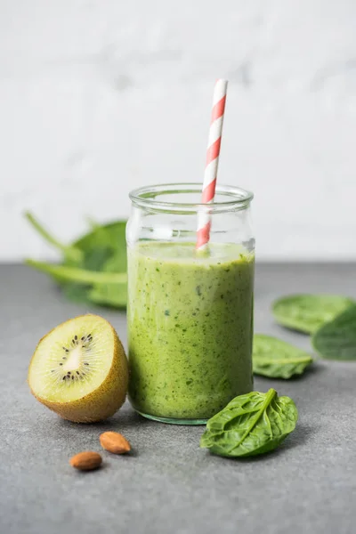 Kiwi, spinach leaves and green organic smoothie in glass with straw — Stock Photo