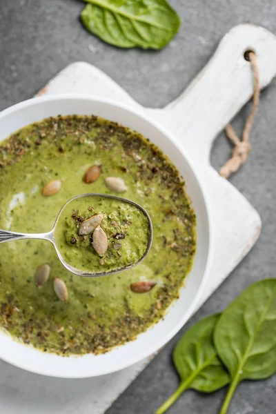 Закрыть серебряную ложку с зеленым овощным сливочным супом в миске — стоковое фото