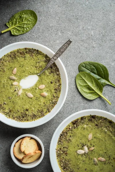 Vista dall'alto di due ciotole con zuppa verde di spinaci cremosi e crostini — Foto stock