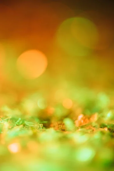 Fond lumineux avec des paillettes orange et vert avec bokeh — Photo de stock