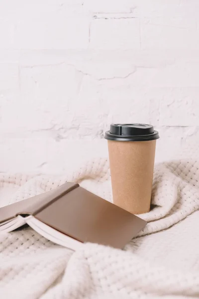 Nahaufnahme von Buch und Einweg-Kaffeetasse auf weißer Decke — Stockfoto