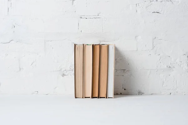 Books near white brick wall, educational background — Stock Photo