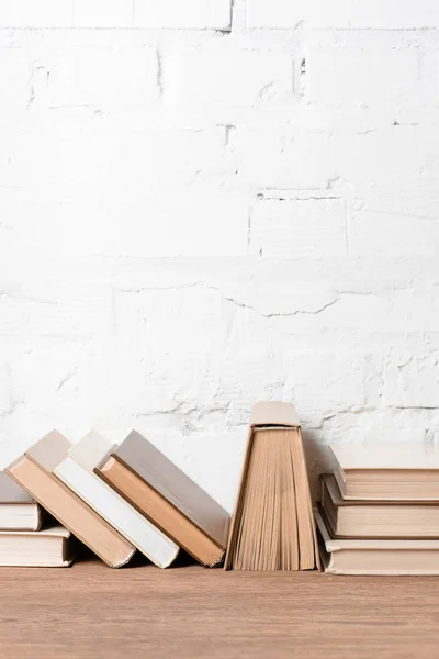 Books with hardcovers on wooden table near white brick wall — Stock Photo