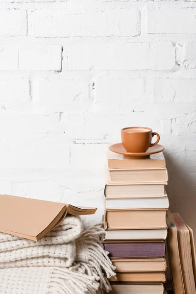Tasse de café sur pile de livres près du mur de briques blanches — Photo de stock