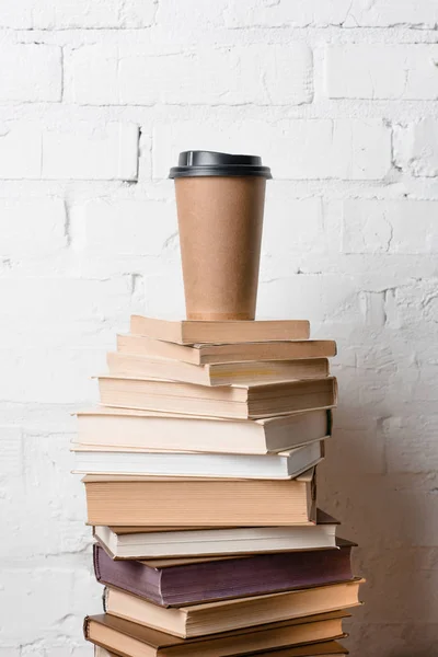 Café para ir em pilha de livros perto de parede de tijolo branco — Fotografia de Stock