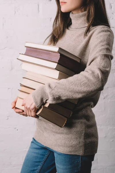 Plan recadré de jeune femme tenant pile de livres — Photo de stock