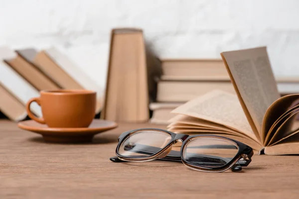 Vue rapprochée des lunettes, tasse de café et livres sur table en bois — Photo de stock