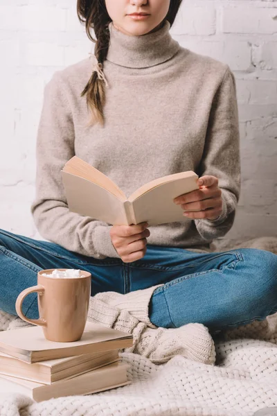 Tasse de chocolat chaud avec guimauves et livre de lecture fille derrière — Photo de stock