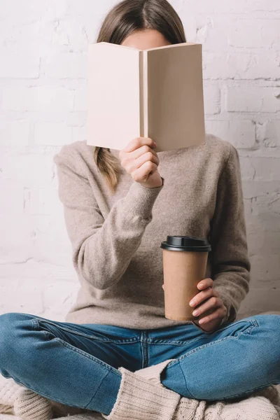 Дівчина тримає книгу і каву, щоб піти в паперовий стаканчик — Stock Photo