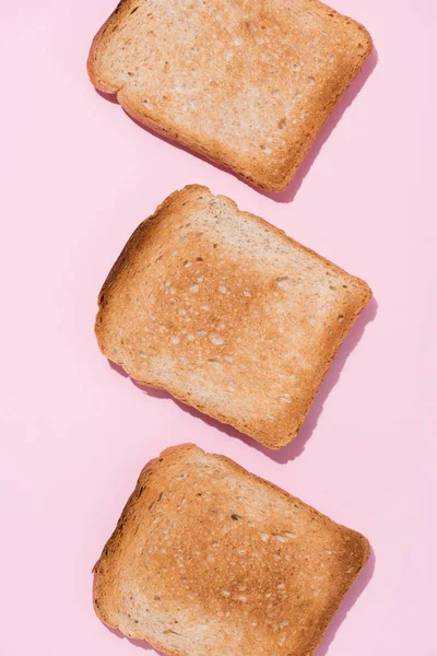 Top view of row of delicious toasts on pink surface — Stock Photo