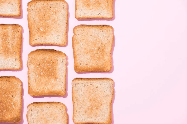 Draufsicht auf Reihen knuspriger Toasts auf rosa Oberfläche — Stockfoto