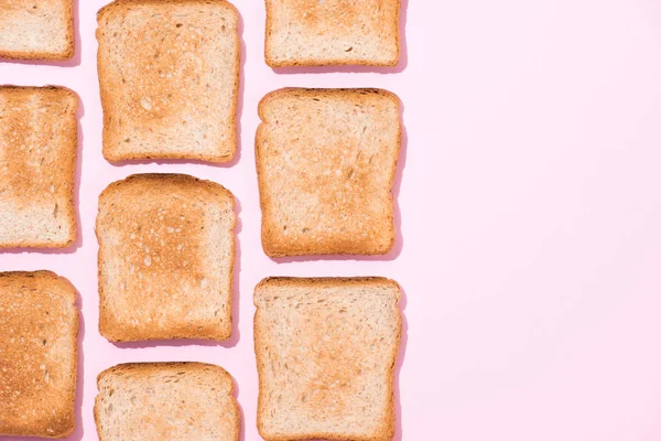 Vista superior de filas de tostadas crujientes en la superficie rosa - foto de stock