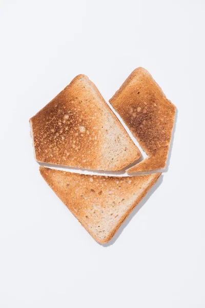 Vista superior de la forma del corazón hecha de pan tostado en la superficie blanca - foto de stock