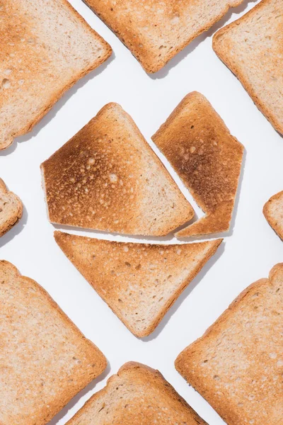 Top view of heart shape made of grunchy toast with slices of bread around on white surface — Stock Photo