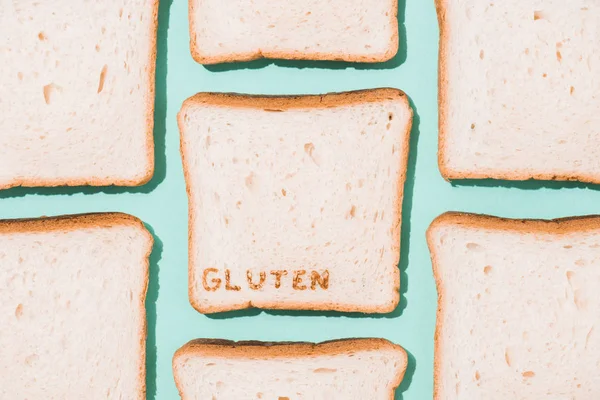 Vista superior de rebanadas de pan con signo de gluten en la superficie azul - foto de stock