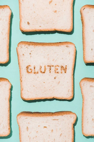 Vue du dessus des tranches de pain avec panneau gluten brûlé sur la surface bleue — Photo de stock