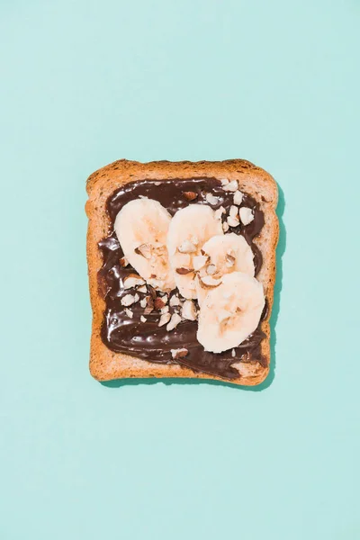 Draufsicht auf köstlichen Toast mit Schokoladenpaste und Banane auf blauer Oberfläche — Stockfoto