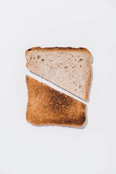 Draufsicht auf eine Scheibe Brot mit gerösteter Hälfte auf weißer Oberfläche — Stockfoto