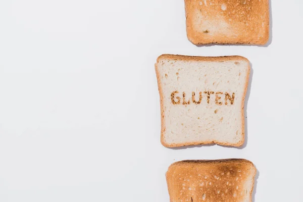 Vue du haut de la rangée de toasts et tranche de pain avec panneau gluten brûlé sur la surface blanche — Photo de stock