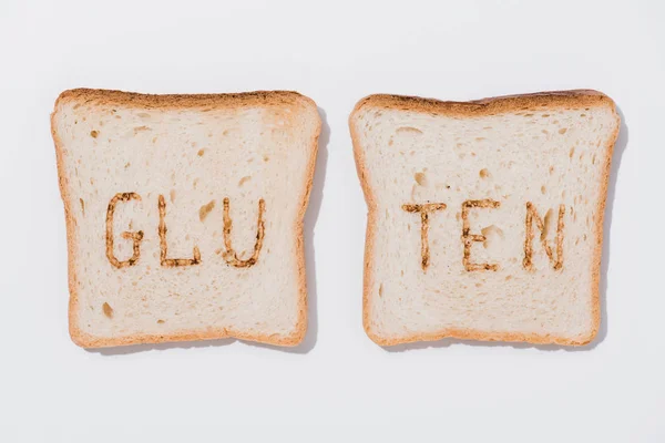 Vista superior de rebanadas de pan con signo de gluten quemado en la superficie blanca — Stock Photo