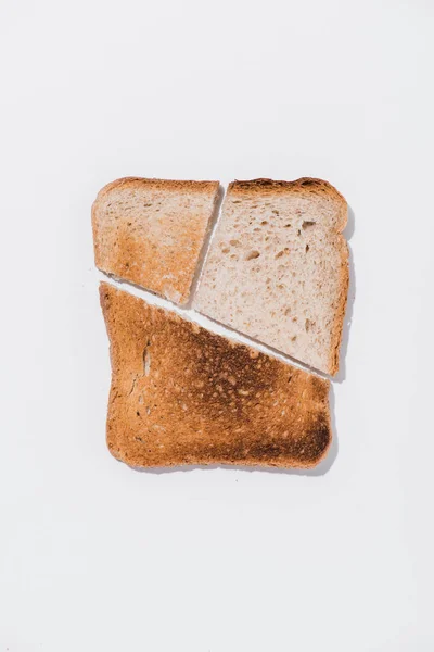 Vista superior de rebanada de pan con trozos asados en la superficie blanca - foto de stock