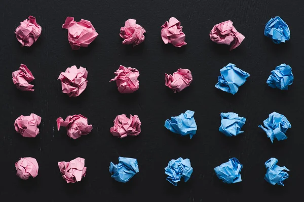 Vista superior de organizadas bolas de papel rosa e azul amassado no fundo preto, pensar conceito diferente — Fotografia de Stock