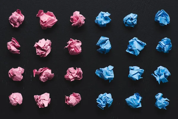 Top view of arranged pink and blue crumpled paper balls on black background, think different concept — Stock Photo
