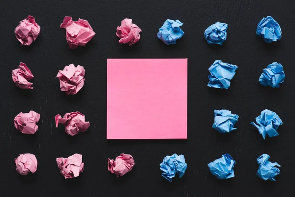 Vista superior de bolas de papel rosadas e azuis amassadas com nota pegajosa no fundo preto, pense conceito diferente — Fotografia de Stock