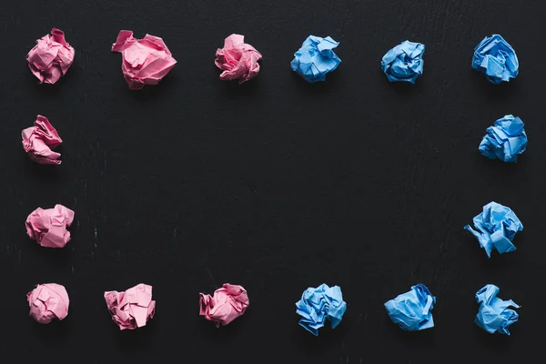 Draufsicht auf Rahmen aus rosa und blau zerknüllten Papierkugeln auf schwarzem Hintergrund, anderes Konzept — Stockfoto