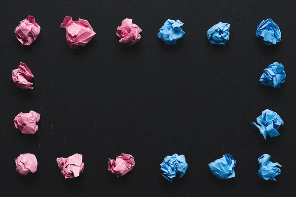 Vista dall'alto della cornice fatta di palline di carta spiegazzate rosa e blu su sfondo nero, pensare concetto diverso — Foto stock