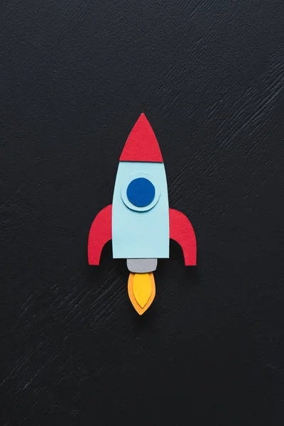 Top view of flying paper rocket on black background, setting goals concept — Stock Photo