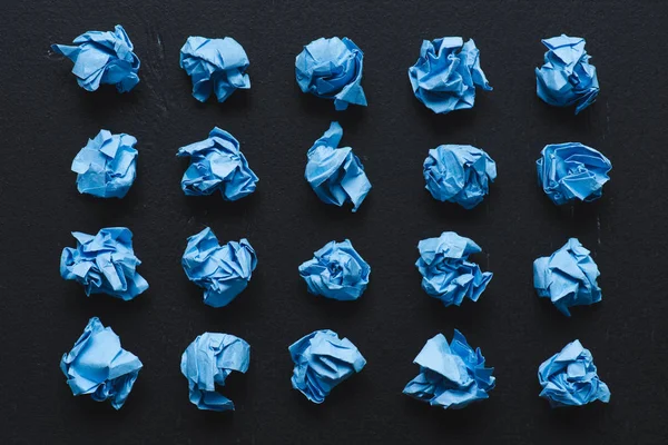 Vue du dessus des boules de papier froissées bleues sur fond noir, penser concept différent — Photo de stock