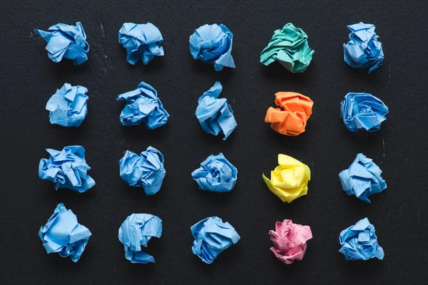 Vista dall'alto di palle di carta accartocciate con fila di quelle colorate su sfondo nero, pensare concetto diverso — Foto stock