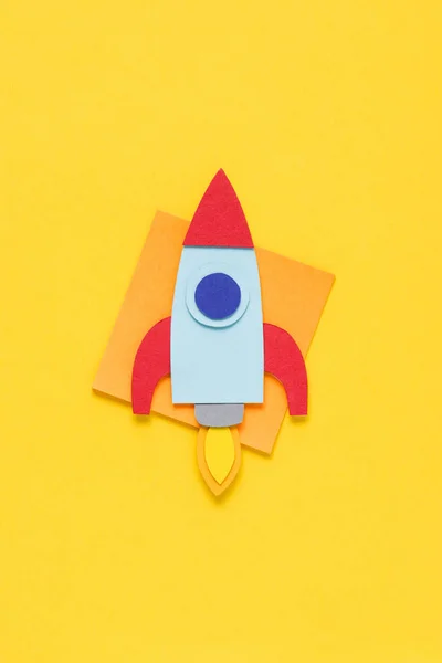 Vue du dessus de la fusée en papier volant sur fond jaune, fixant le concept des objectifs — Photo de stock
