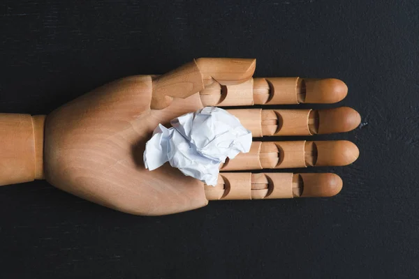 Draufsicht auf weiße zerknüllte Papierkugel auf Holzhand mit schwarzem Hintergrund, anderes Konzept — Stockfoto