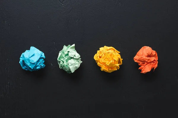 Top view of arranged colorful crumpled paper balls on black background, think different concept — Stock Photo