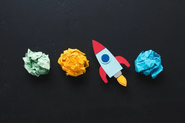 Top view of cardboard rocket with crumpled paper balls on black background, setting goals concept — Stock Photo