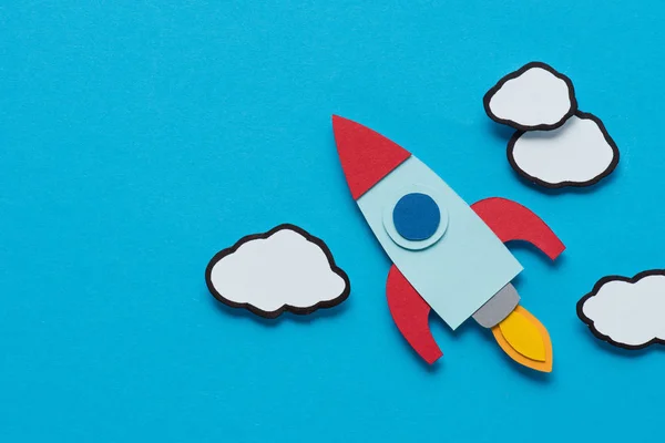 Top view of cardboard rocket with clouds on blue background, setting goals concept — Stock Photo