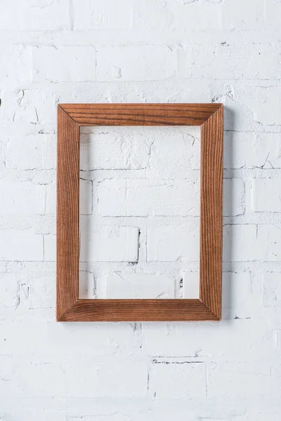 Brown empty frame hanging on white brick wall — Stock Photo