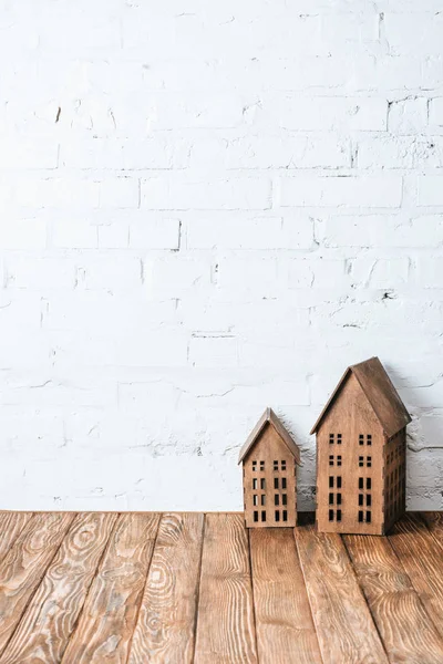 Modelos de casa rústica na mesa de madeira perto da parede de tijolo branco — Fotografia de Stock