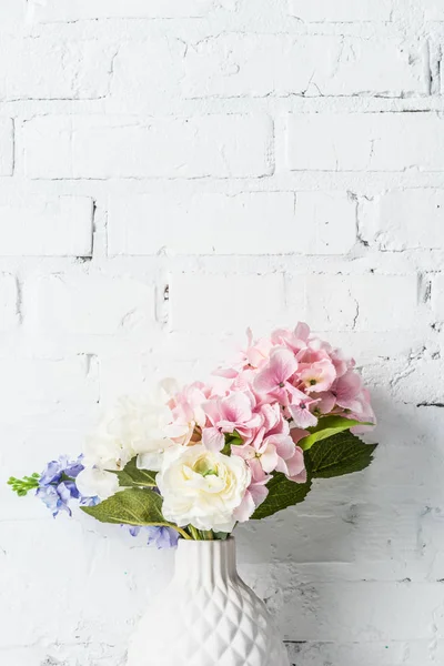 Bouquet in vaso di ceramica vicino al muro di mattoni bianchi — Foto stock
