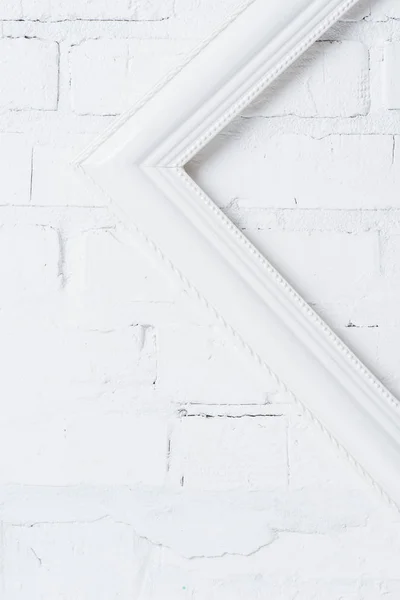 Nahaufnahme des schiefen weißen leeren Rahmens, der an der Ziegelwand hängt — Stockfoto