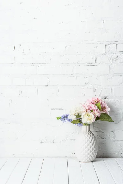 Keramikvase mit Blumenstrauß auf rustikalem Holztisch nahe Ziegelmauer — Stockfoto