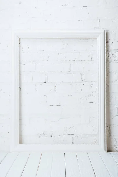 Біла порожня рамка на сільському дерев'яному столі біля цегляної стіни — стокове фото