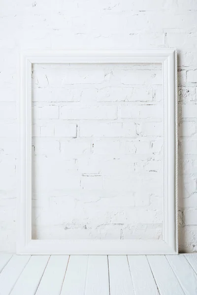 White empty frame on rustic wooden table near brick wall — Stock Photo