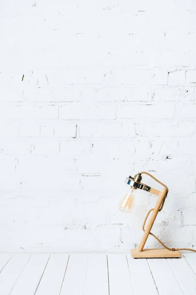 Lampe de table sur table en bois blanc près du mur de briques — Photo de stock