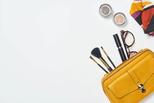 Vista dall'alto di sciarpa, occhiali, mascara, pennelli cosmetici, ombretto e borsa su sfondo bianco — Foto stock